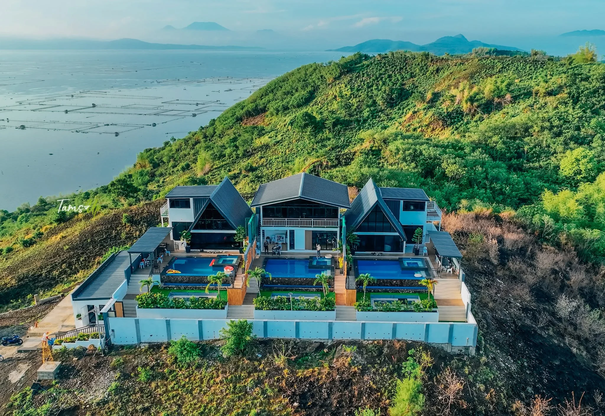 An aerial view of the villas against green hills and the lake at City on a Hill