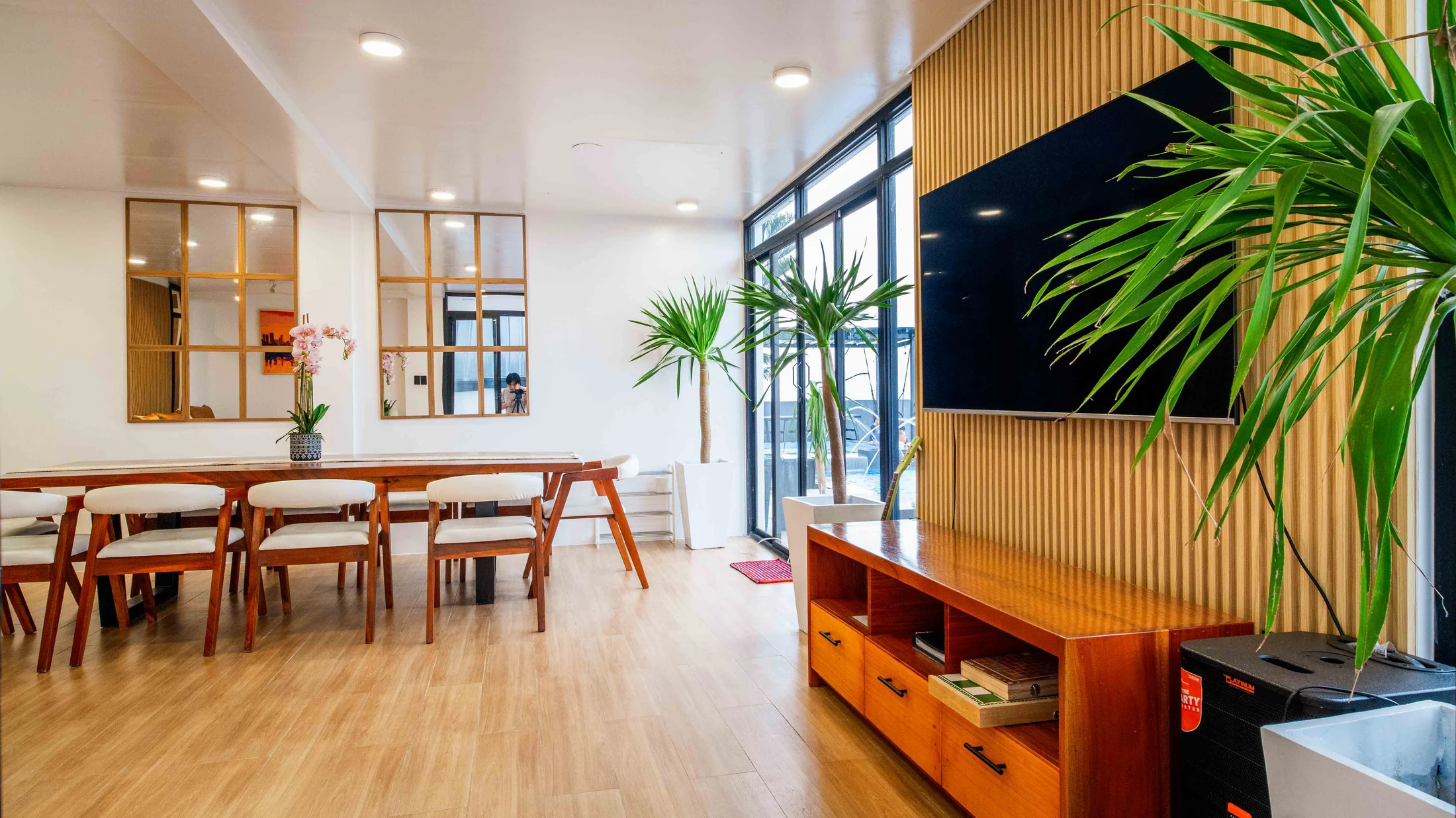 Zoie’s open living and dining space with a timber ceiling and full-height windows at City on a Hill