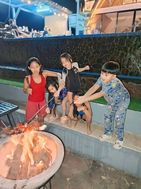 Children roasting marshmallows over the fire pit at night.