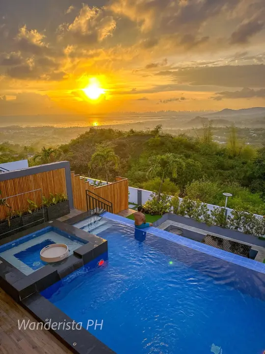A guest at the infinity edge as the sun sets over the lake and the city skyline.