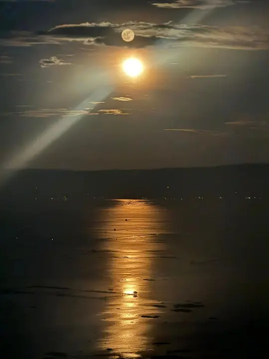 The full moon rising over Laguna Lake, its light trailing across the water.