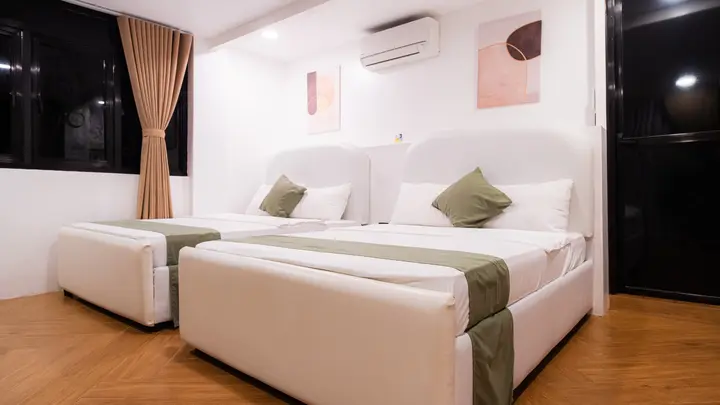 Two double beds with white upholstered headboards and soft abstract prints.