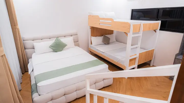 A queen bed with a tufted headboard beside a timber bunk bed.
