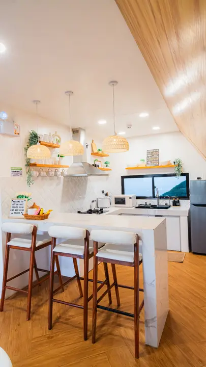 A villa kitchen bar with three stools under rattan pendants.