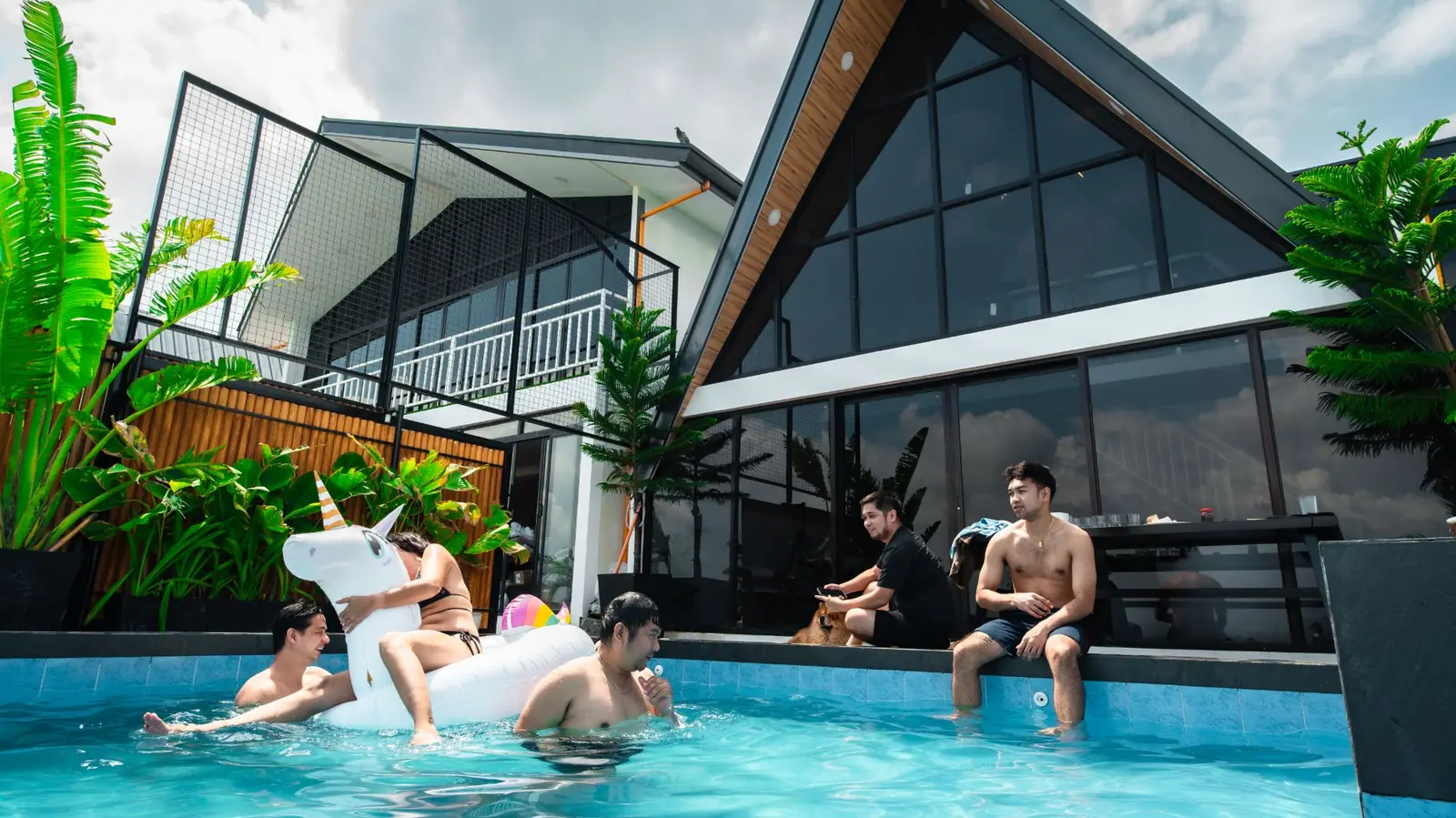 Guests swimming and relaxing around Zuriel’s pool beside the A-frame.