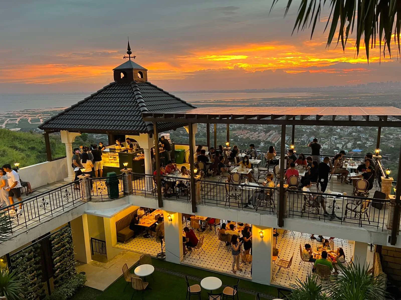 A gazebo-roofed café terrace in Angono lit up against an orange sunset