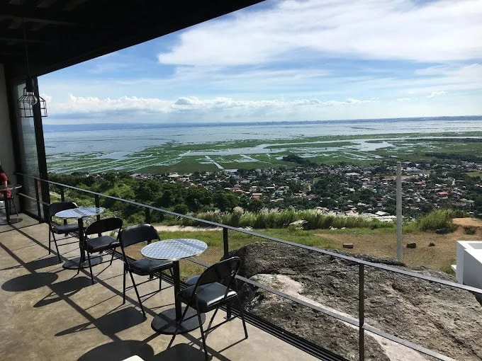An open-air café terrace with tables overlooking Laguna Lake and the Rizal lowlands
