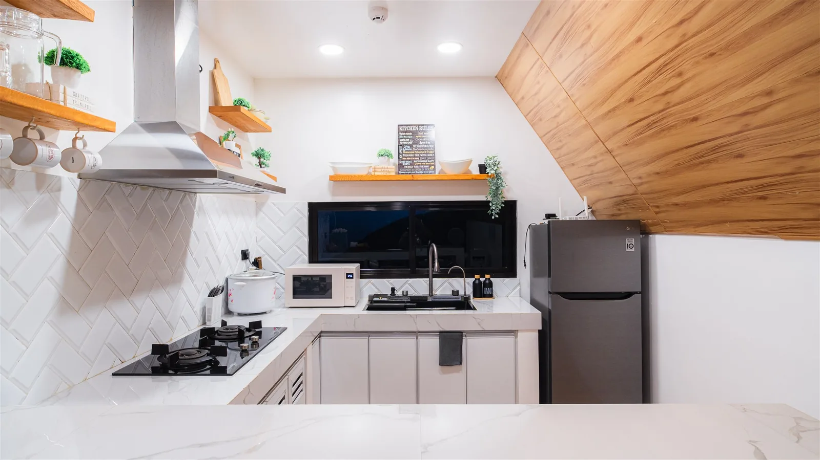 Villa kitchen with white cabinets, a range hood, cooktop and refrigerator