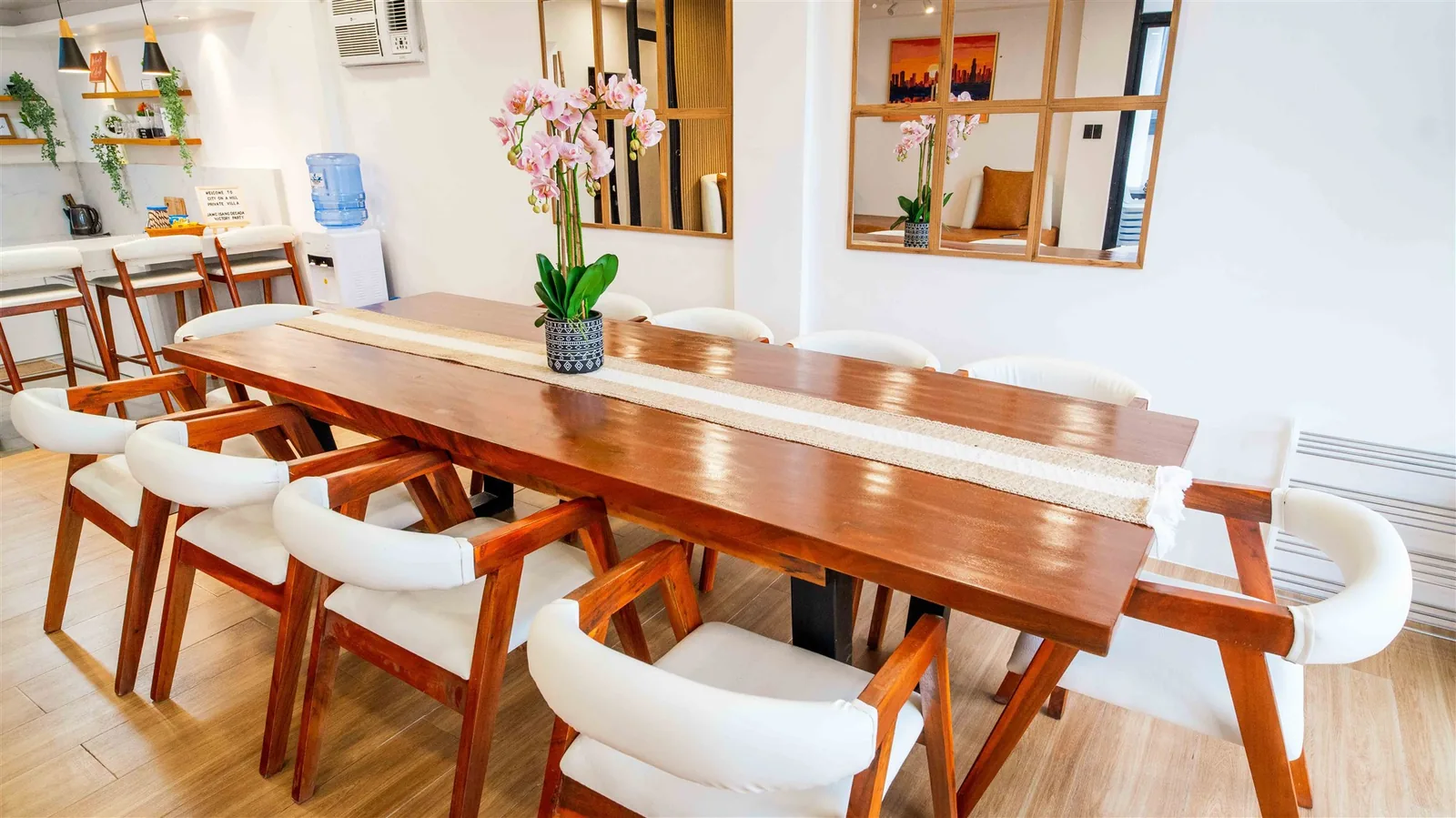 Zoie villa dining table seating a large group, with a wall-mounted TV beyond
