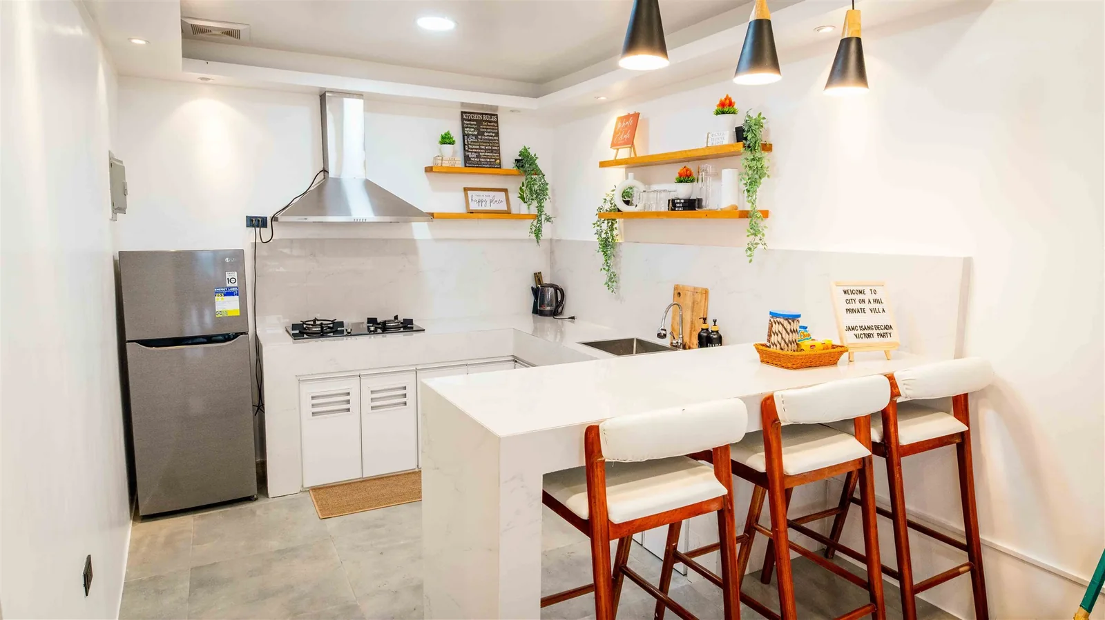 Zoie villa kitchen with a breakfast bar, bar stools, refrigerator and range hood