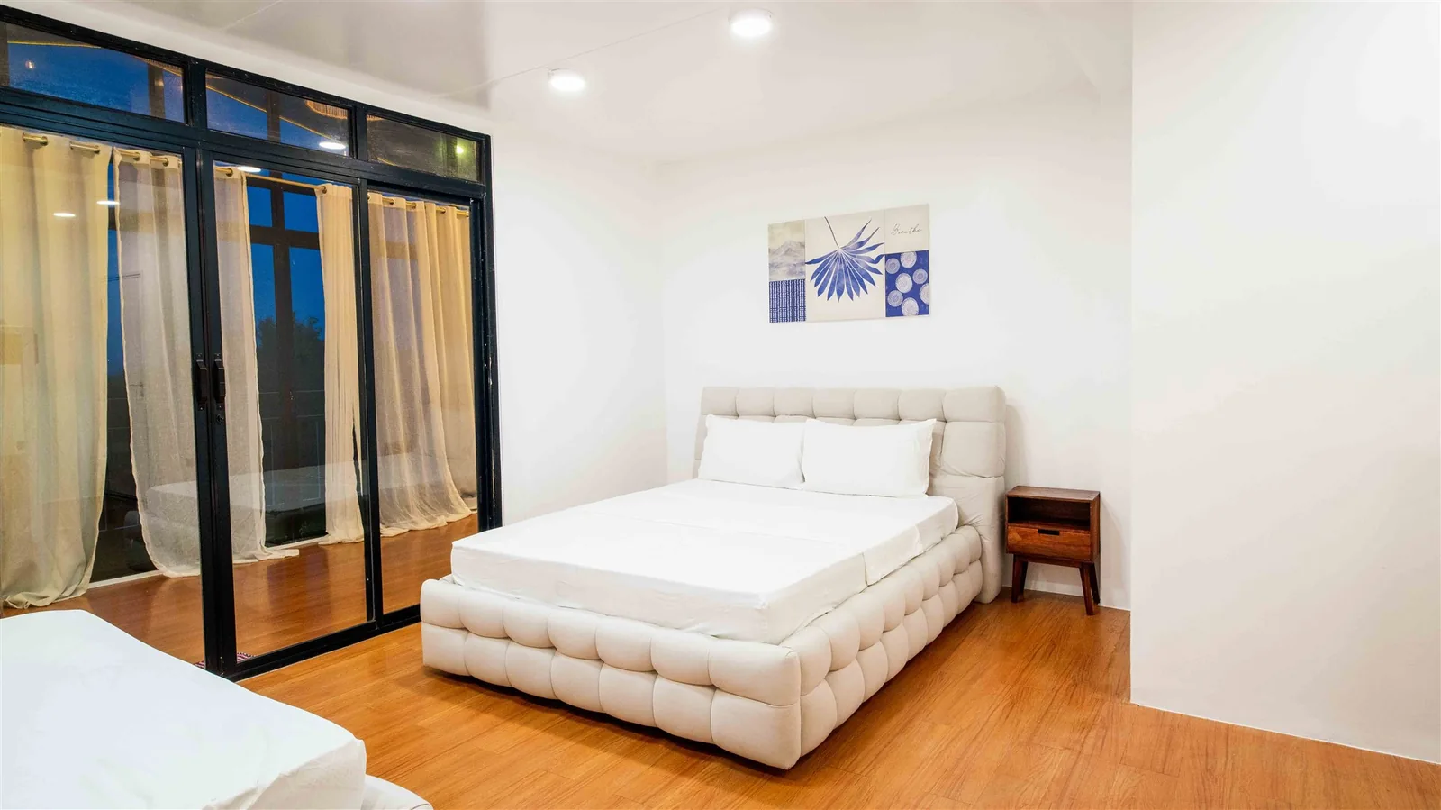 Bright Zoie villa bedroom with a large white bed and glass doors