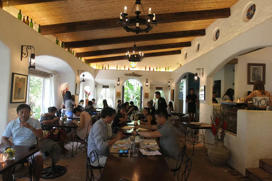 A busy Antipolo restaurant dining room with wooden beams, chandeliers and arched doorways
