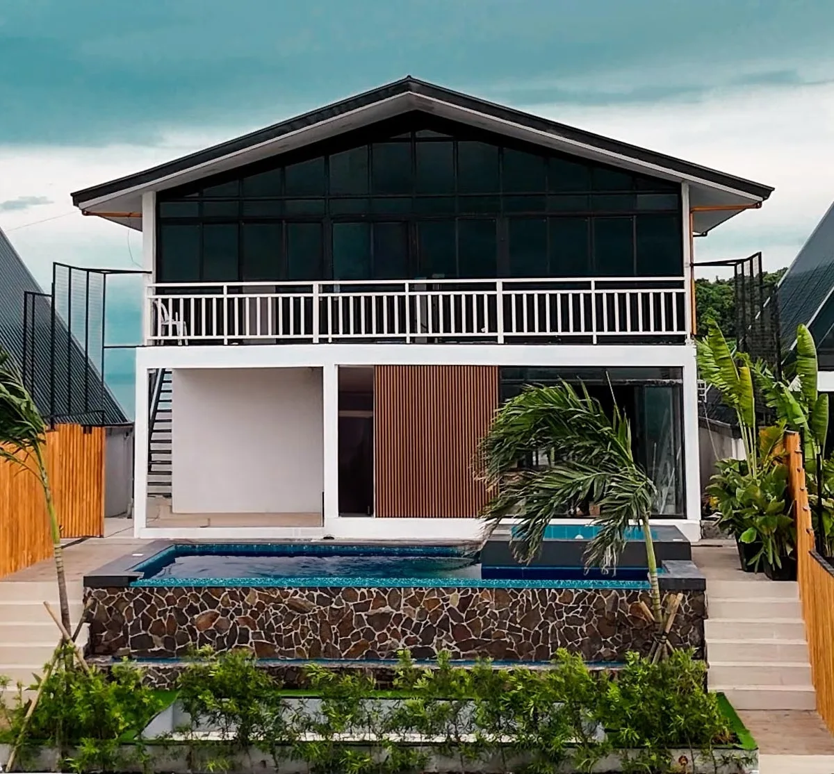 Zoie: a broad-roofed two-storey villa with a long white balcony and a pool below.