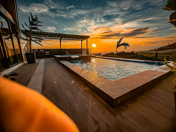 Sunset over Zuriel’s pool deck, with palms and the landscape beyond.